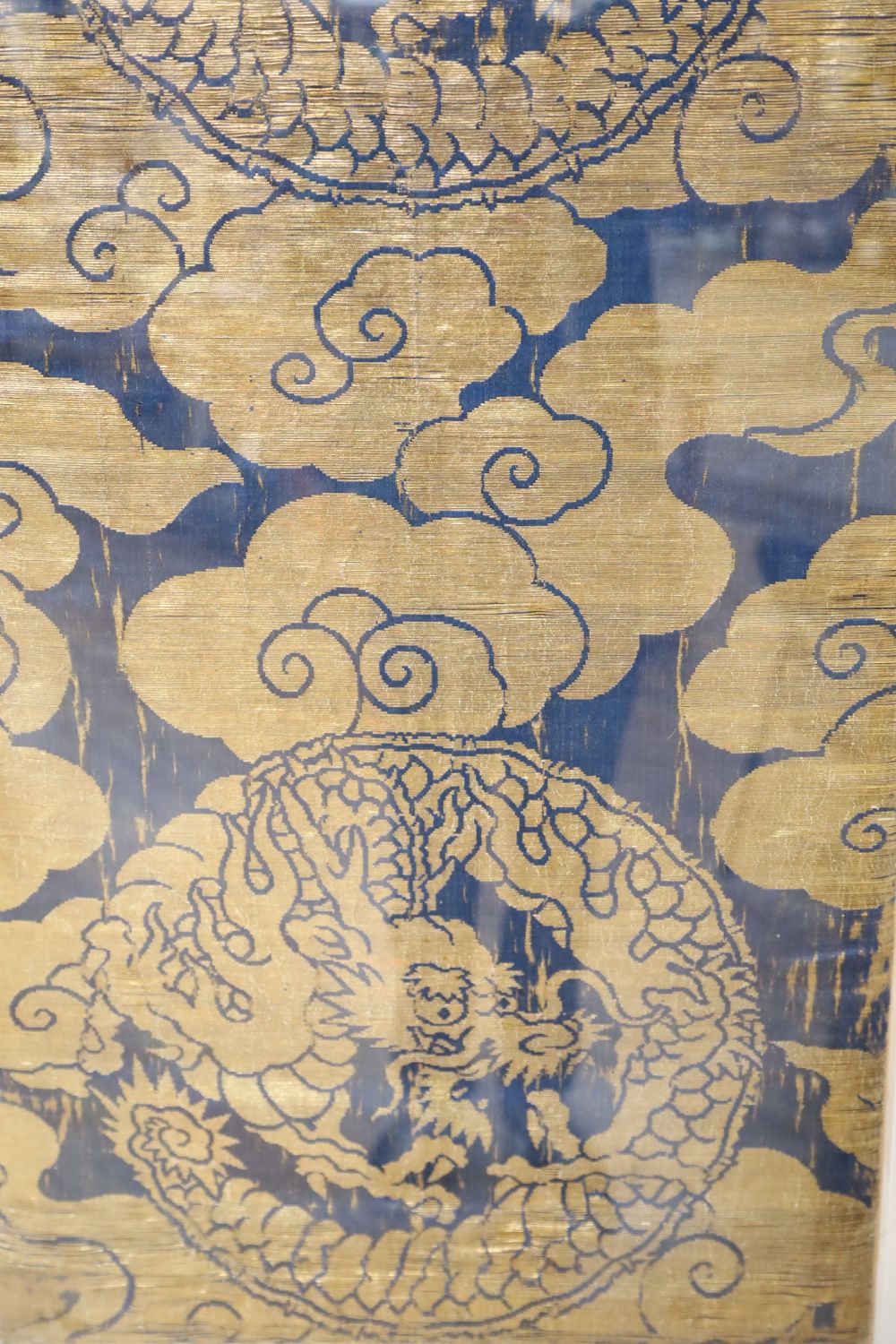 A Chinese gold thread embroidered panel, depicting celestial dragons amongst stylised clouds